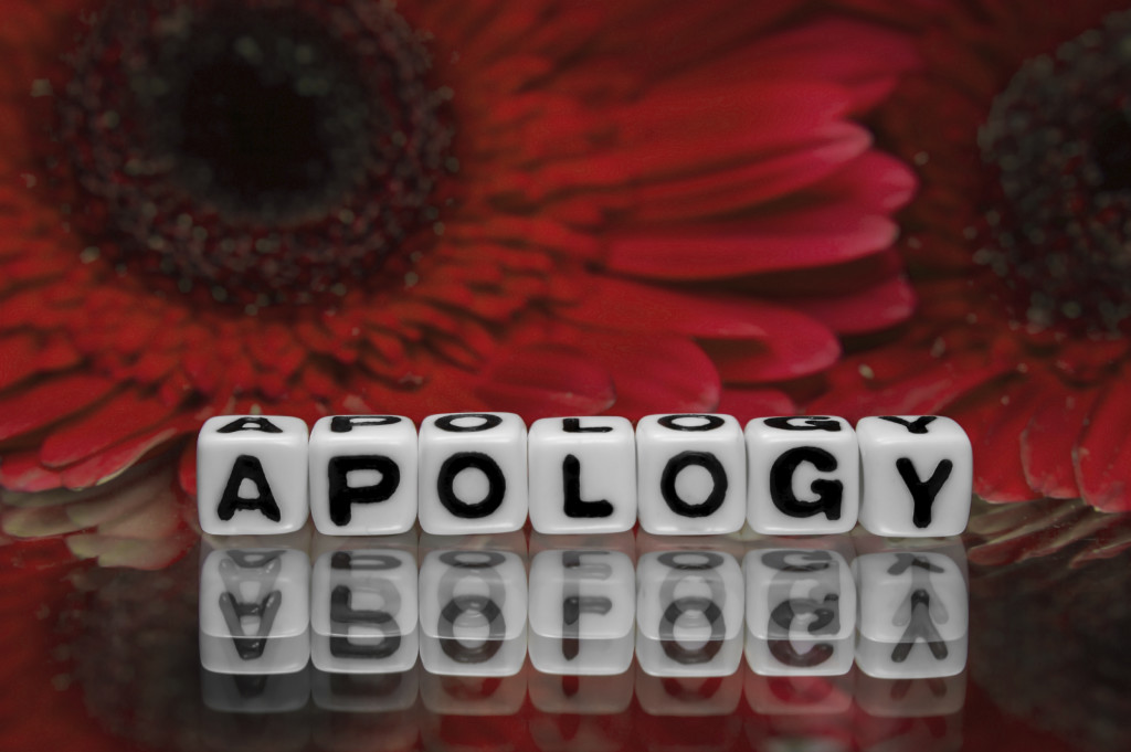 Apology text message with red flowers in the background.